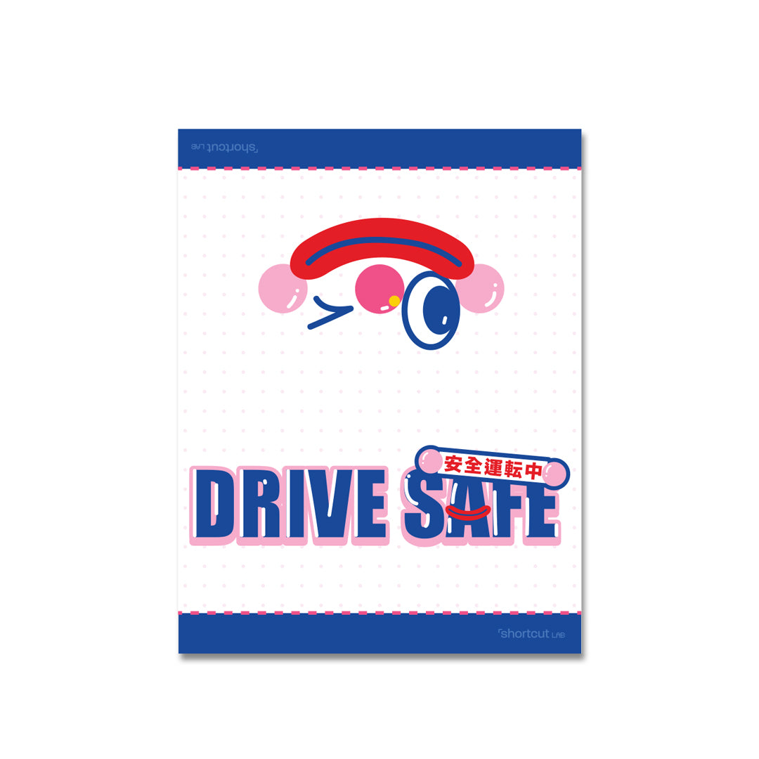 Shortcut Lab ‘Drive Safe’ reflective car tag packaging featuring winking clown face and Japanese text above bold blue-pink typography.