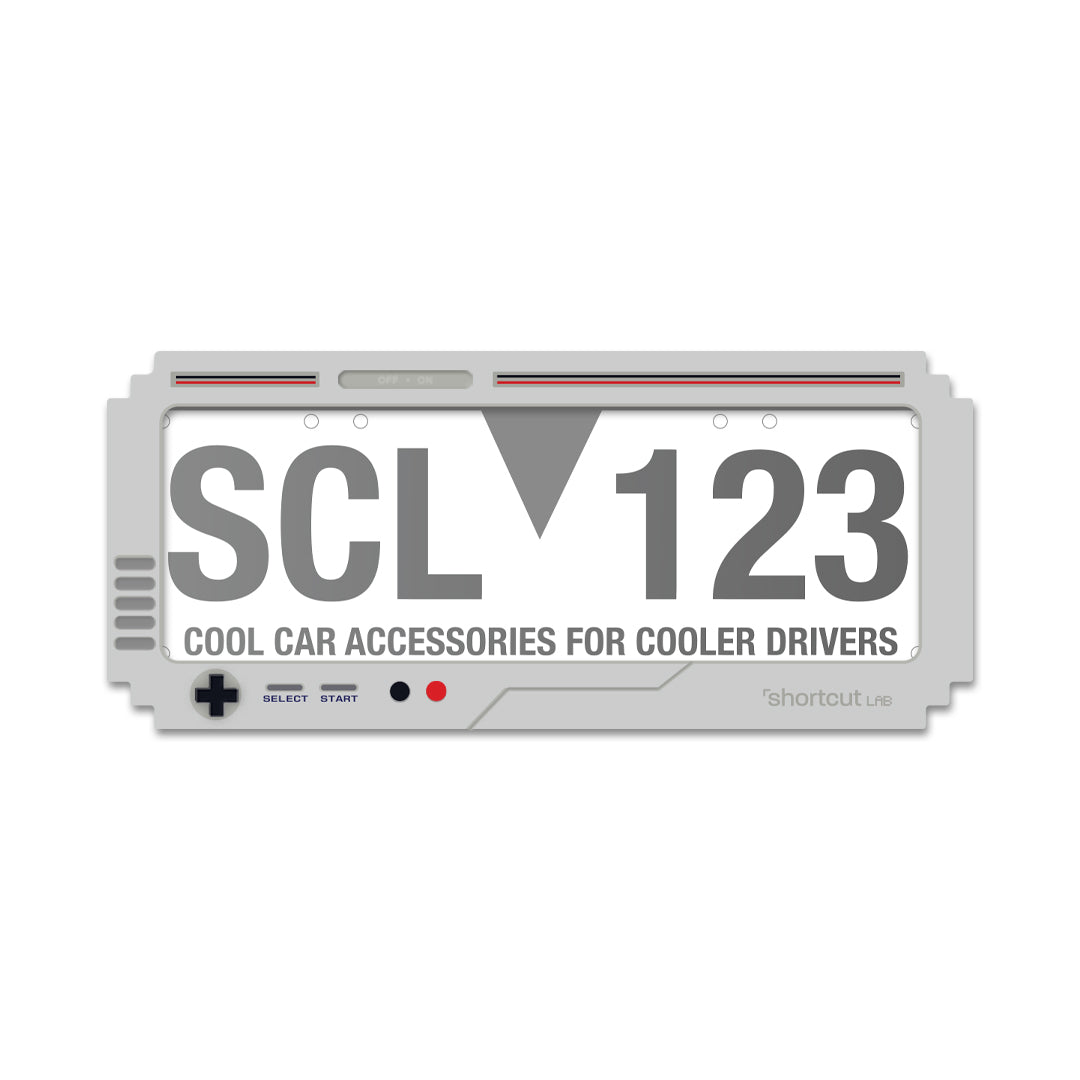 Shortcut Lab GameBoy-inspired car number plate frame in grey with retro console design featuring buttons and text ‘Cool Car Accessories for Cooler Drivers.